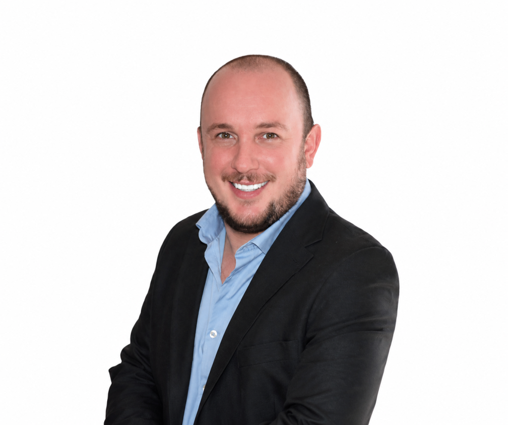Headshot of a smiling man in a black blazer and light blue shirt against a white background.