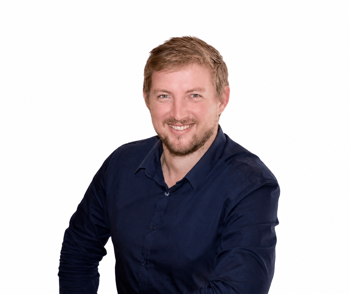 Smiling man in a dark navy dress shirt against a white background, looking at the camera.